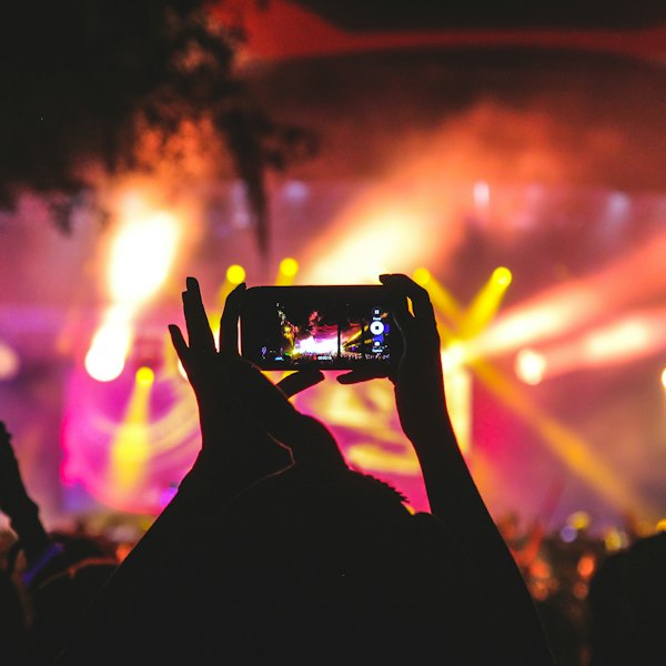 Fã filmando o show com o celular no meio do público